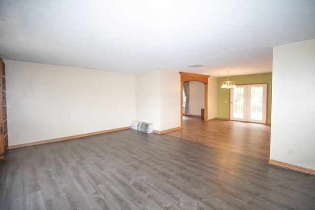 empty room with a chandelier and dark hardwood / wood-style flooring