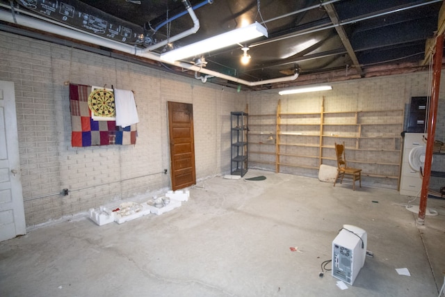 basement featuring washer / dryer and brick wall