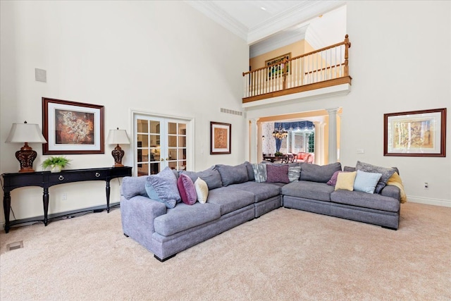 carpeted living room with decorative columns, crown molding, french doors, and a towering ceiling