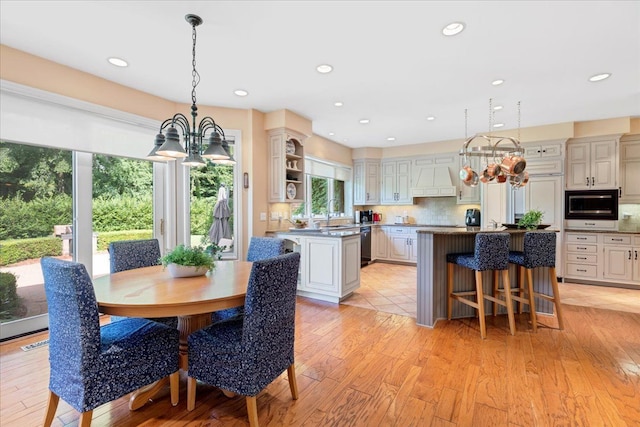 dining space featuring sink, light hardwood / wood-style floors, and an inviting chandelier