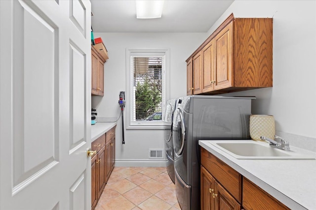 washroom with washing machine and dryer, sink, light tile patterned flooring, and cabinets