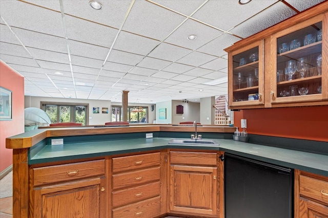 kitchen featuring kitchen peninsula, sink, a drop ceiling, and fridge