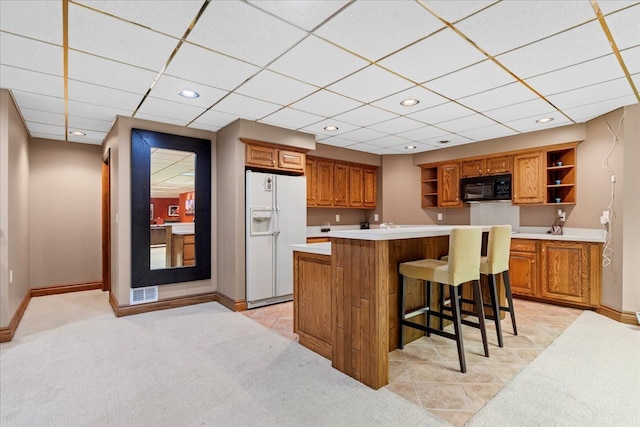 kitchen with a kitchen breakfast bar, light colored carpet, and white fridge with ice dispenser