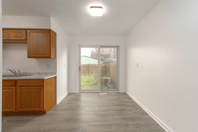 kitchen with tasteful backsplash, light hardwood / wood-style flooring, and sink