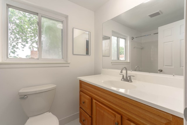 bathroom with vanity, toilet, and tiled shower