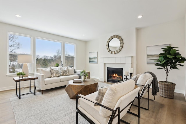 living room featuring recessed lighting, light wood-style flooring, baseboards, and a tile fireplace