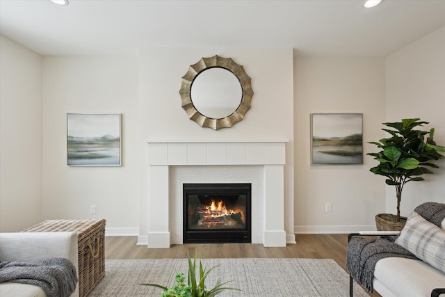 living area with light wood finished floors, a fireplace, baseboards, and recessed lighting