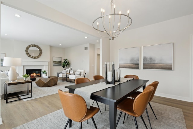 dining space featuring recessed lighting, baseboards, wood finished floors, and a glass covered fireplace