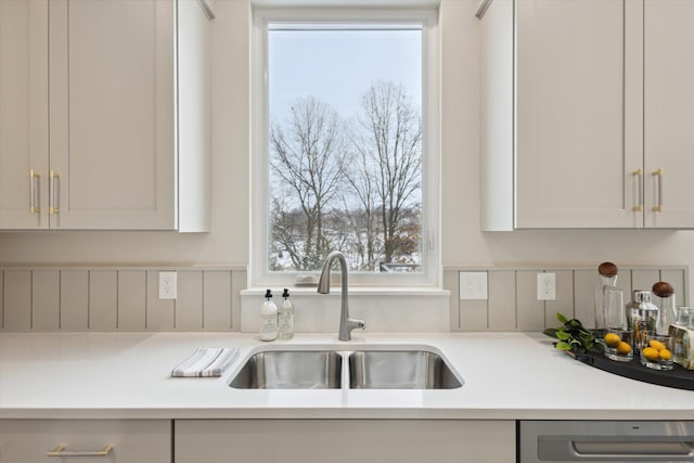 kitchen with stainless steel dishwasher, a wealth of natural light, light countertops, and a sink