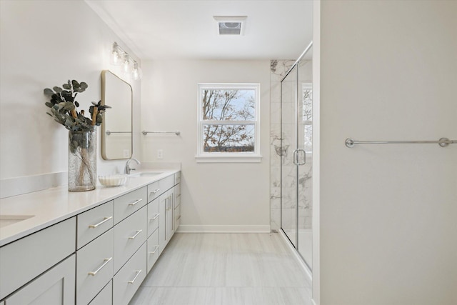 bathroom with double vanity, a marble finish shower, baseboards, visible vents, and a sink