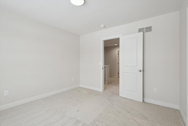 unfurnished bedroom with light carpet, visible vents, and baseboards