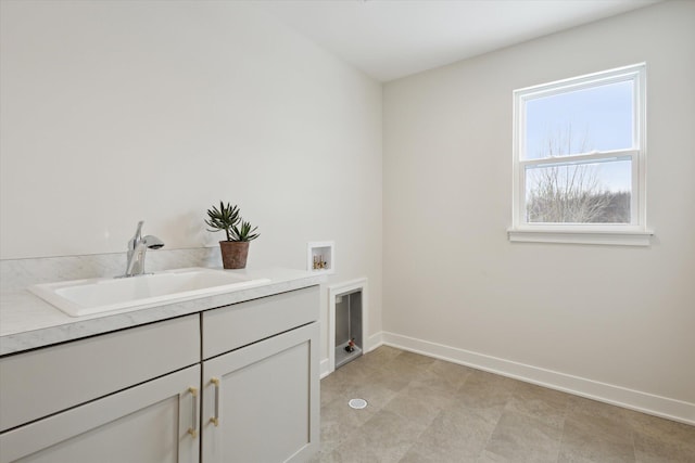 laundry area with cabinet space, baseboards, washer hookup, and a sink