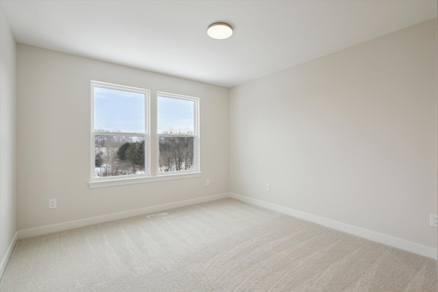 unfurnished room with carpet, visible vents, and baseboards