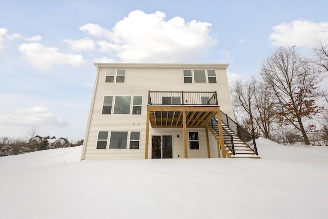 snow covered rear of property with a deck and stairway