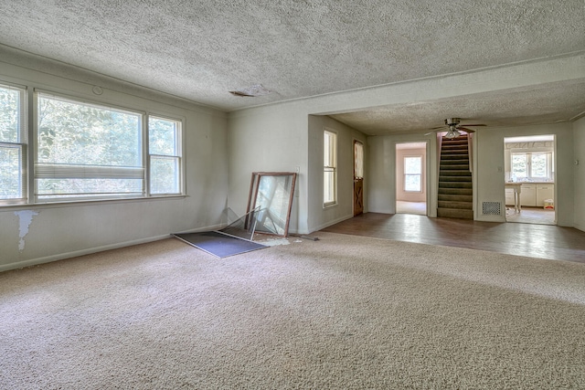 carpeted spare room featuring ceiling fan and a textured ceiling