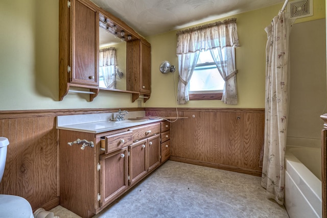 bathroom with vanity, shower / bath combo with shower curtain, and wooden walls