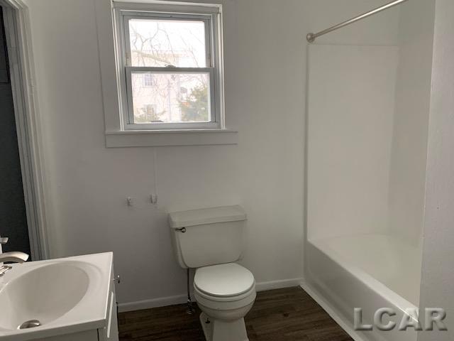 551 Tabor St, Adrian, MI 49221 - full bath with baseboards, toilet, vanity, and wood finished floors