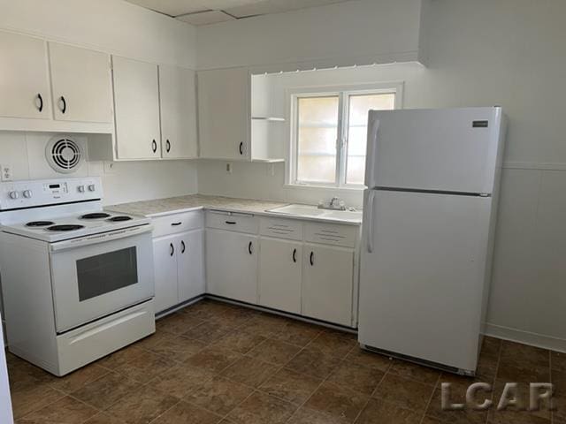 kitchen with white appliances, white cabinetry, and sink