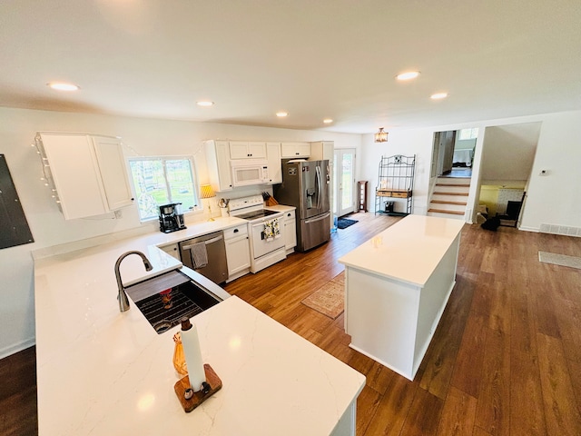 kitchen featuring white cabinets, a kitchen island, dark hardwood / wood-style flooring, and appliances with stainless steel finishes