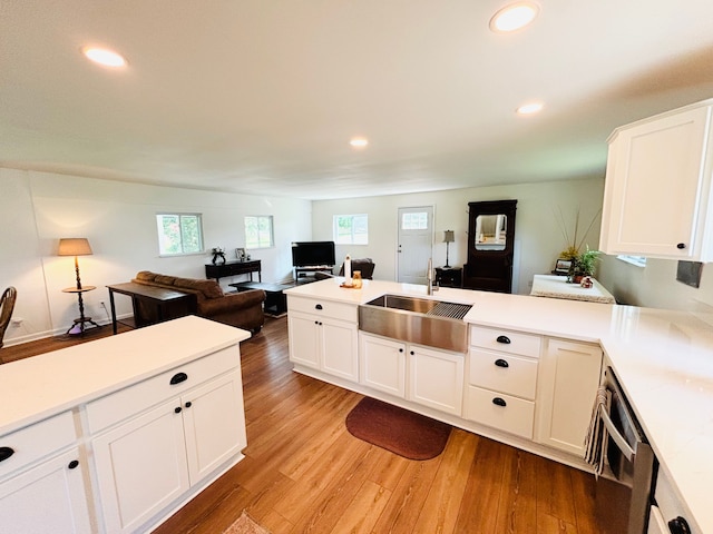 kitchen featuring kitchen peninsula, white cabinetry, sink, and light wood-type flooring