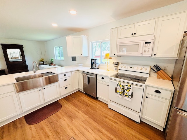 kitchen featuring kitchen peninsula, light wood-type flooring, stainless steel appliances, sink, and white cabinetry