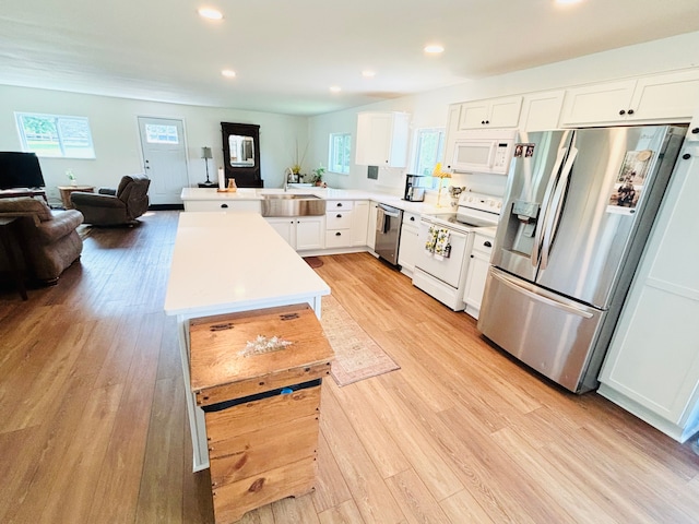 kitchen featuring kitchen peninsula, appliances with stainless steel finishes, light wood-type flooring, a healthy amount of sunlight, and white cabinets