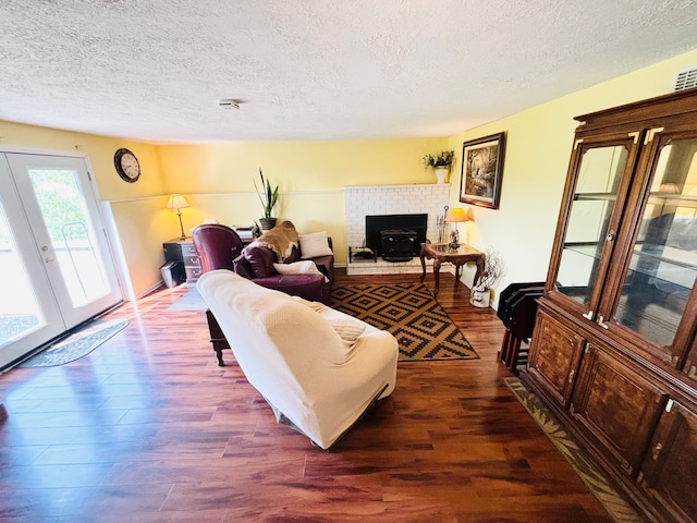 living room with a fireplace, dark hardwood / wood-style flooring, a textured ceiling, and french doors