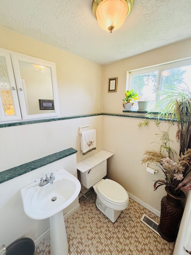 bathroom with toilet and a textured ceiling