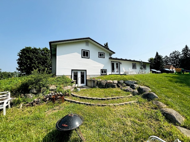 rear view of property with a yard, french doors, and a fire pit