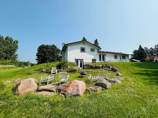 rear view of property with french doors and a lawn