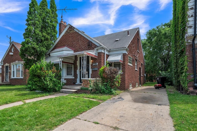 bungalow featuring covered porch and a front yard