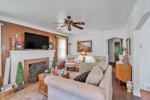 living room with hardwood / wood-style floors, ceiling fan, and wooden walls