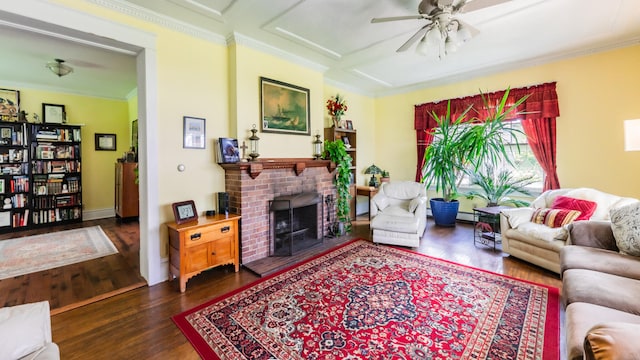 living room featuring dark hardwood / wood-style flooring, baseboard heating, ceiling fan, crown molding, and a fireplace