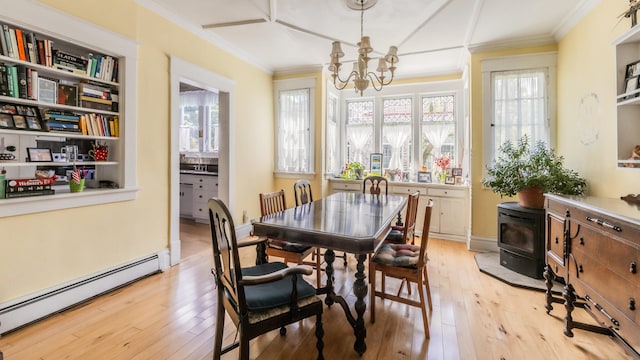 dining area with a wood stove, a chandelier, light hardwood / wood-style floors, and a baseboard radiator