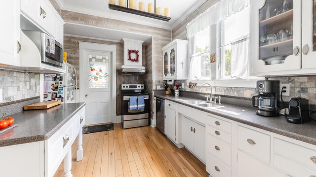 15 S Broad St, Hillsdale, MI 49242 - kitchen featuring stainless steel appliances, a sink, dark countertops, decorative backsplash, and white cabinetry