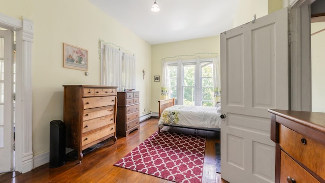 bedroom featuring dark wood-type flooring and a baseboard heating unit