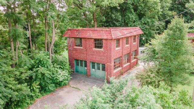 15 S Broad St, Hillsdale, MI 49242 - view of side of property with brick siding, a wooded view, and mansard roof