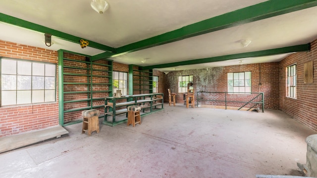 interior space featuring beamed ceiling and brick wall