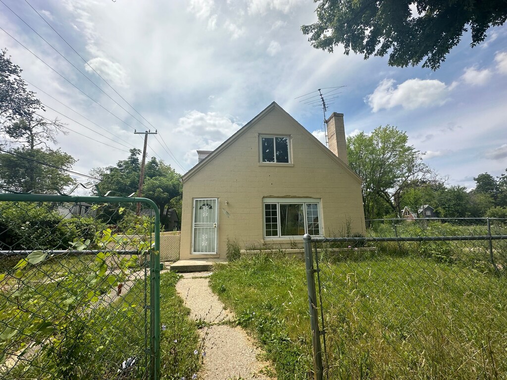 19531 Anvil St, Detroit, MI 48205 - view of front of property featuring a gate, a chimney, and concrete block siding