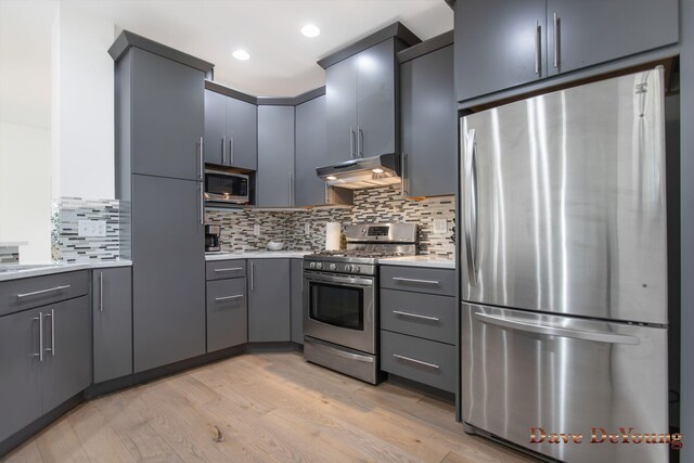 kitchen with backsplash, stainless steel appliances, light hardwood / wood-style floors, and gray cabinetry