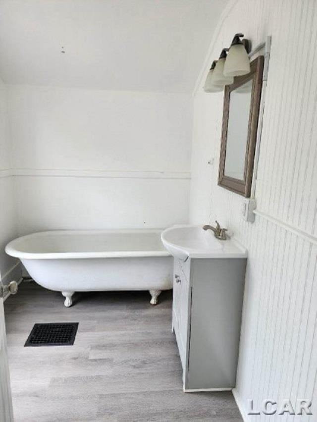 bathroom with wood-type flooring, vanity, and a tub to relax in