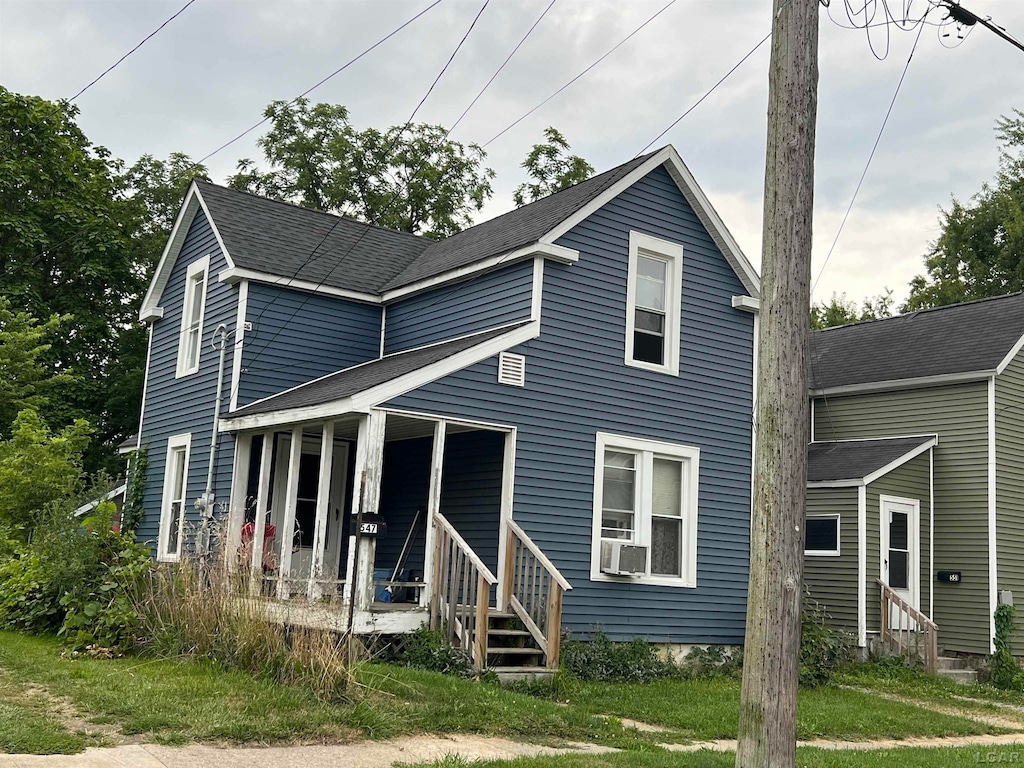 view of front of house with a porch, cooling unit, and a front lawn