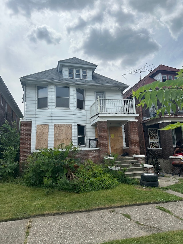 view of front of house featuring a balcony and a front lawn