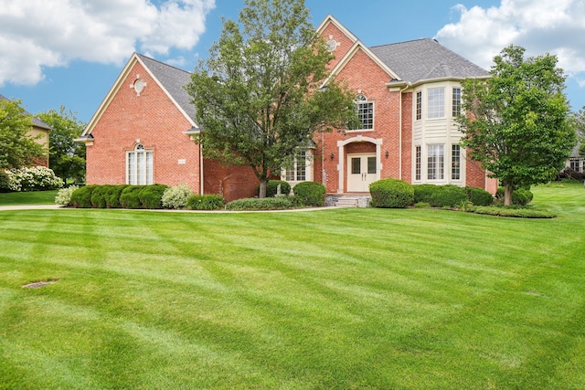 view of front facade with brick siding and a front yard