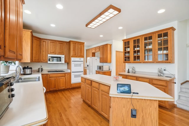 kitchen featuring white appliances, a kitchen island, a sink, and light countertops