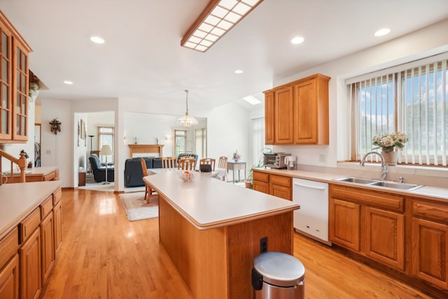 kitchen featuring white dishwasher, light countertops, light wood-style floors, and a sink