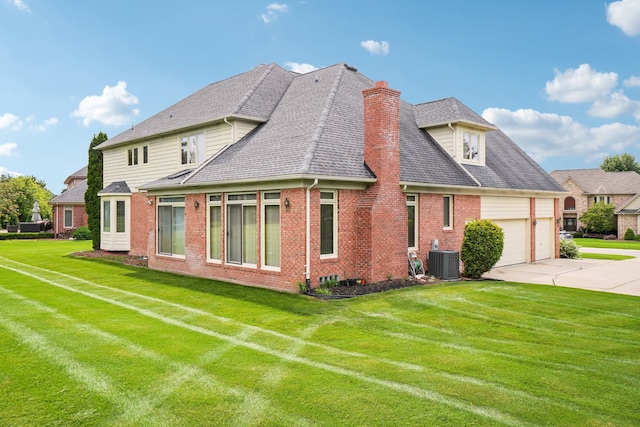 rear view of property featuring a chimney, brick siding, central AC unit, concrete driveway, and a yard