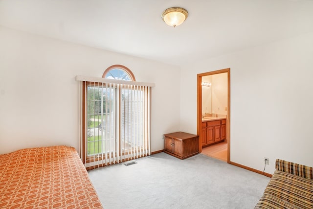 unfurnished bedroom featuring visible vents, baseboards, ensuite bath, and light colored carpet