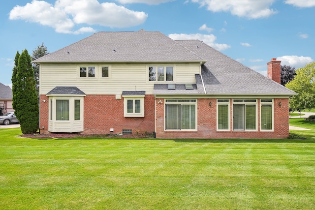 rear view of house with a lawn, a chimney, roof with shingles, and brick siding