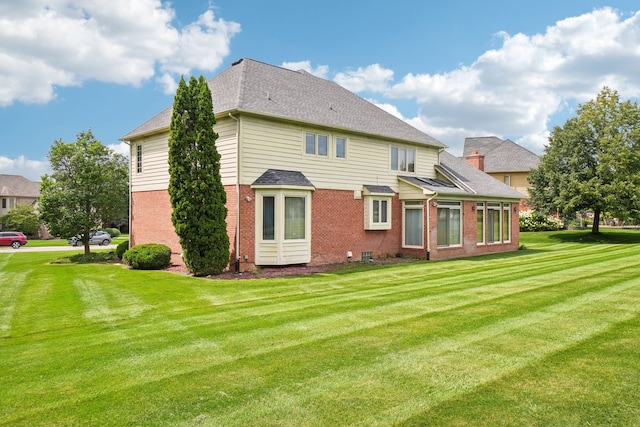 back of property featuring roof with shingles, a yard, and brick siding